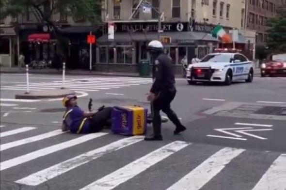 فيديو| شرطي يعتدي على عامل توصيل أثناء مرور موكب الرئيس الأمريكي
